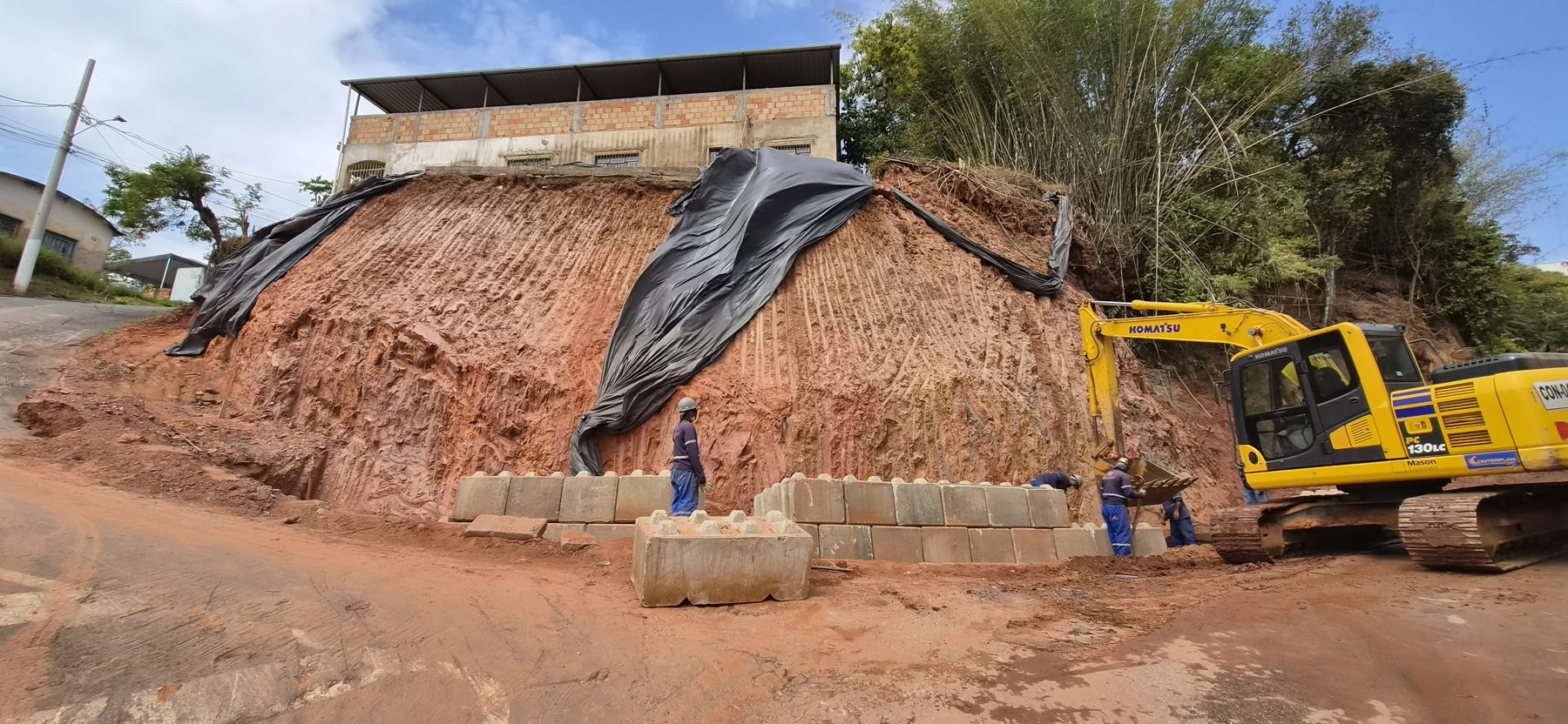 Contenção de talude com blocos de concreto intertravados e escavadeira em obra
